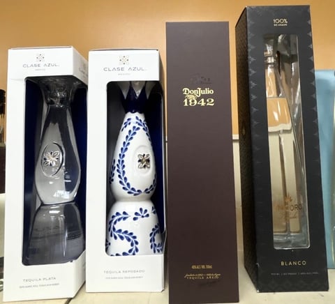 Collection of premium tequila and mezcal bottles in decorative packaging, including Clase Azul and Don Julio 1942 bottles