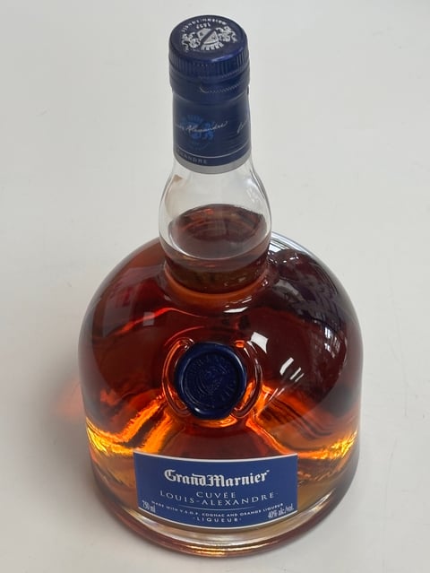 Bottle of Grand Marnier liqueur with amber liquid, blue cap and label on white background