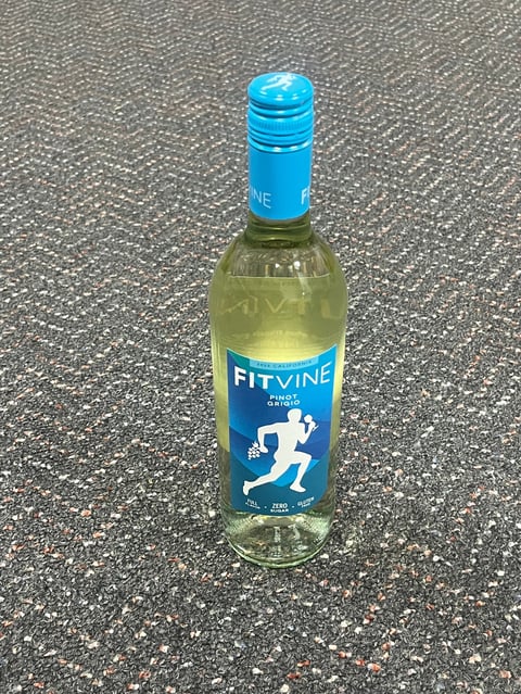 Bottle of Fitvine white wine with blue label and cap on textured gray surface