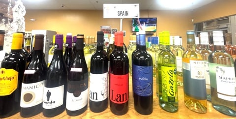 Display of Spanish wines and bottles arranged in a row, labeled with Spain sign, featuring red, white, and rosé varieties