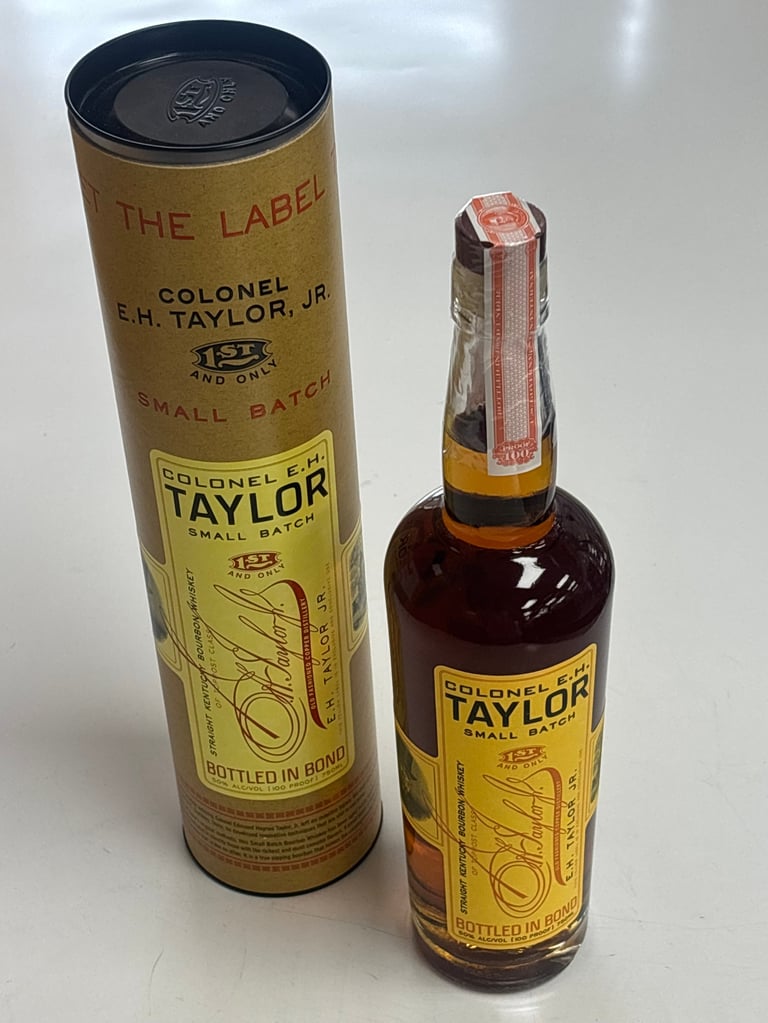 Colonel E.H. Taylor Jr. bourbon whiskey bottle next to its original cylindrical cardboard tube packaging