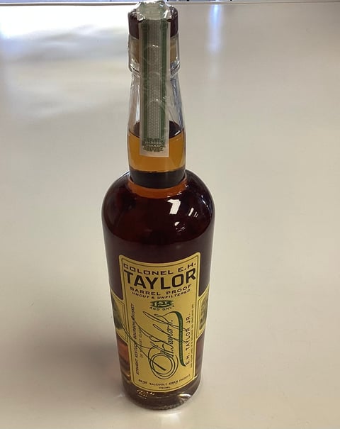 Bottle of Colonel E.H. Taylor barrel proof bourbon whiskey with foil cap on white surface