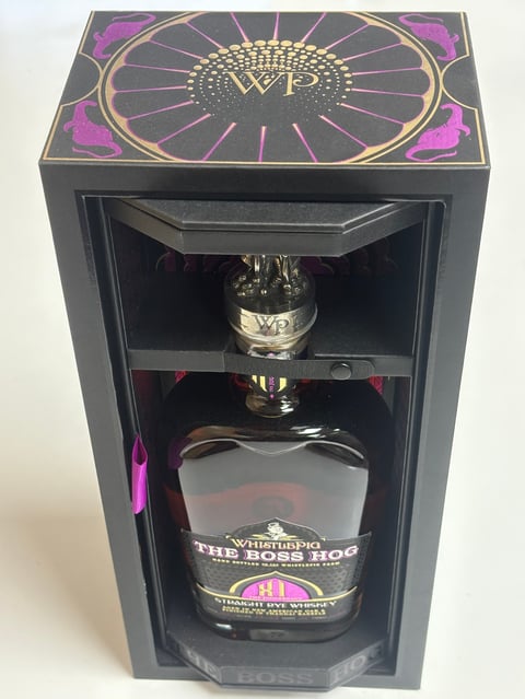 Whiskey bottle gift box with decorative purple and gold design, featuring WP branding and The Boss Hog label inside clear display case