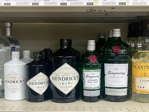Selection of gin bottles arranged on a retail shelf, including Hendricks and Tanqueray brands