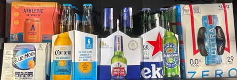 Assortment of colorful beverage bottles and boxes including beer, soda, and energy drink brands arranged in a row