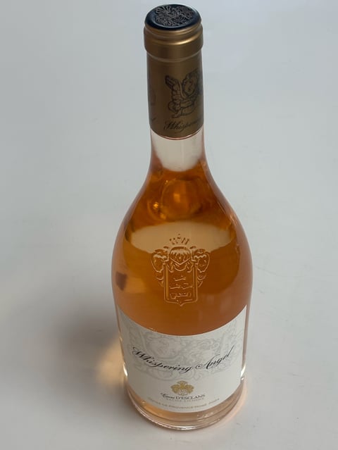 Bottle of rosé wine with bronze foil cap and ornate crest label against white background