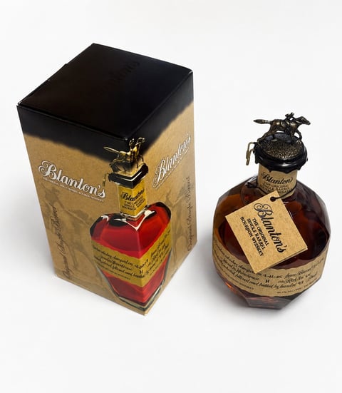 Blantons bourbon whiskey bottle and black box with red heart-shaped design and gold accents on white background